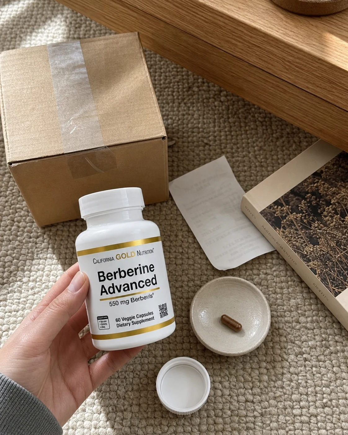 집에서 배송 상자를 열고 Berberine Advanced 라벨을 확인하는 모습